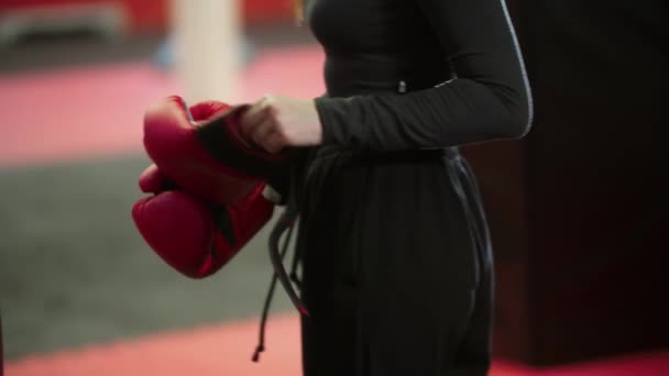 Обучение боксу - привлекательная молодая женщина надевает красные боксерские перчатки — стоковое видео