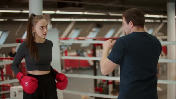 Bokstraining - een aantrekkelijke vrouw die een training volgt met een bokscoach — Stockvideo