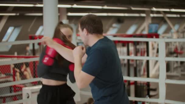 Boks antrenmanı. Çekici bir kadın boks koçuyla antrenman yapıyor. Savunmayı öğreniyor. — Stok video