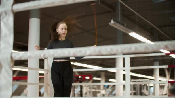 Jeune femme attrayante en vêtements de sport sautant par-dessus la corde sur le ring de boxe — Video