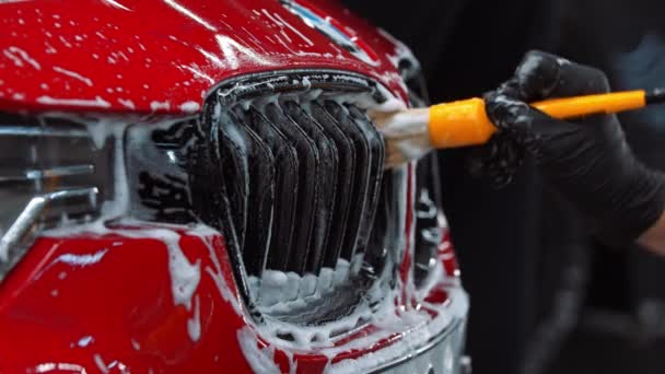 Auto detaillering - man die een reinigingsschuim op de kleine details van een auto met een borstel — Stockvideo