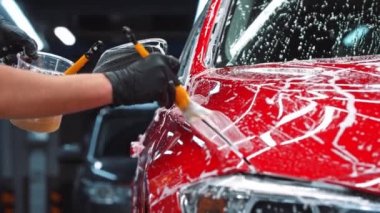 Otomatik temizlik servisi - adam kırmızı arabaya temizlik solüsyonu uyguluyor