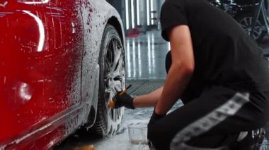 Otomatik temizlik servisi - adam fırça kullanarak araba diskini temizliyor