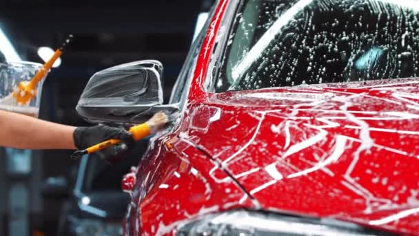 汽车细节- -用刷子在红色轿车上使用清洁剂泡沫的人 — 图库视频影像