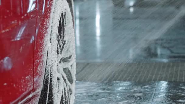 Detallado automático - cubriendo un coche rojo con una espuma de limpieza usando una máquina de pulverización — Vídeos de Stock