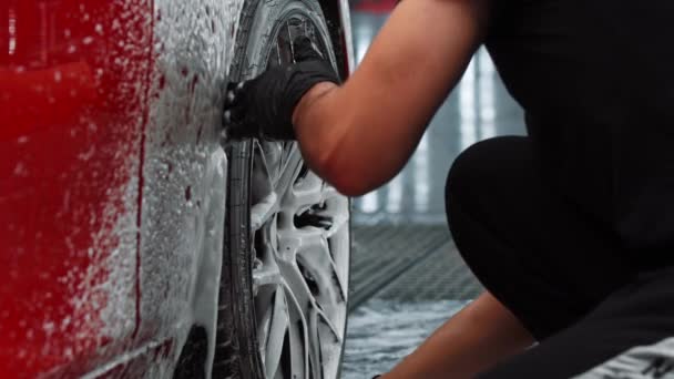 Usługa automatycznego czyszczenia - człowiek czyszczący dysk samochodowy za pomocą szczotki i roztworu do czyszczenia — Wideo stockowe