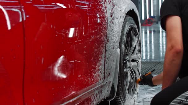 Servicio de limpieza automática: limpieza del disco del coche por el hombre con un cepillo y una solución de limpieza — Vídeos de Stock