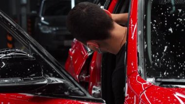 Oto temizleme servisi. Araba kapısını yıkayan işçi.