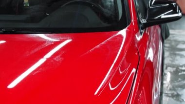 Araba yıkama servisi. Kırmızı arabayı paçavrayla yıkayan bir adam.