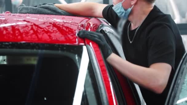 Služba mytí aut - muž pracovník mytí červeného auta s hadrem — Stock video