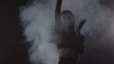 Vogue - karanlık dumanlı odada dans eden genç çekici kadın