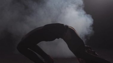 Genç seksi kadın karanlık dumanlı odada dans eder yere uzanır.