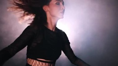 Vogue dumanla dolu stüdyoda dans ediyor. Seksi, aktif dans eden bir kadın.