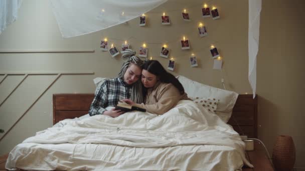 Novias acostadas en la cama y leyendo un libro — Vídeo de stock