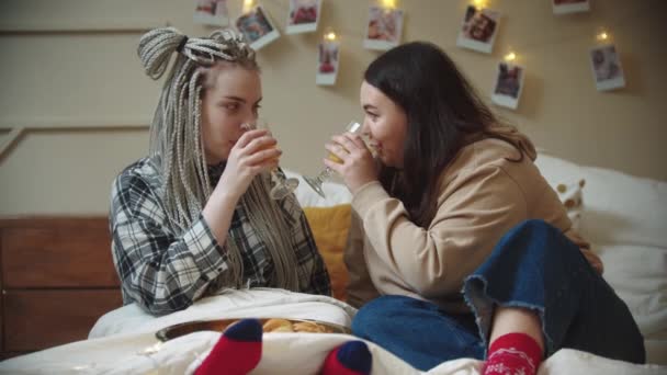 Młode lesbijki jedzące śniadanie w łóżku - pijące sok i słodkie — Wideo stockowe