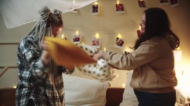 Jóvenes lesbianas jugando con almohadas y abrazándose en la cama — Vídeo de stock