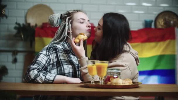 Genç lezbiyen kadınlar birlikte kahvaltı yapıyorlar - arka planda LGBT bayrağı — Stok video
