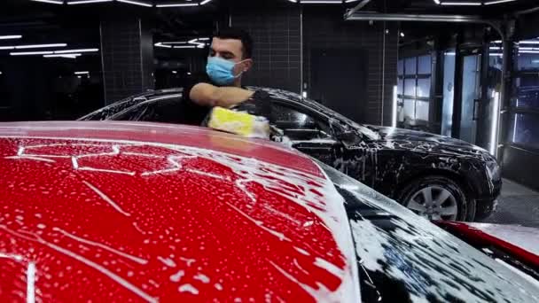 Muž pracovník myje auto pokryté pěnou pomocí velké houby — Stock video