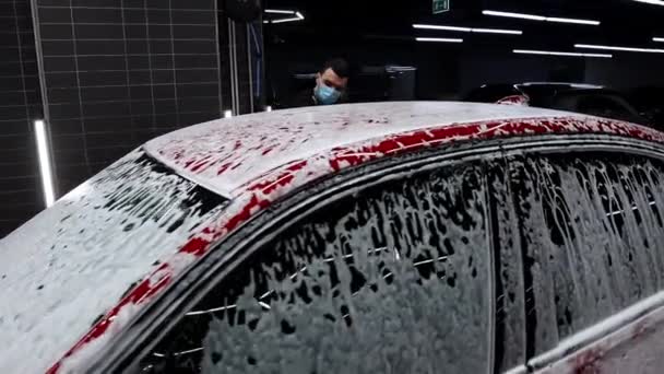 Mann wäscht Auto mit Schaum in Waschsalon — Stockvideo