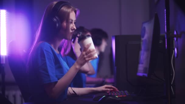 Groupe d'amis assis dans le club de jeu et d'avoir un tournoi de jeu en ligne femme boire du café de la tasse — Video