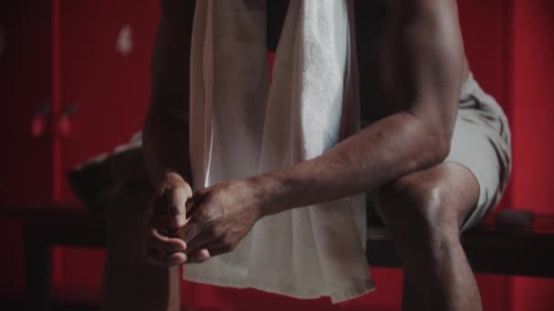 African-american young man sitting in the locker room after shower - looking in the camera — Stock Video