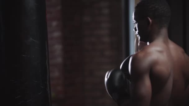 Zwarte jongeman bokser training in de sportschool - ponsen van een bokszak — Stockvideo
