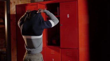 Spor salonundaki soyunma odasında üzerini değiştiren Afro-Amerikan atletik genç adam.