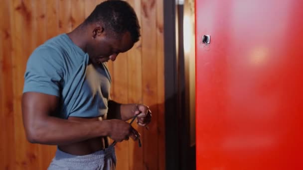 Afro-Amerikaanse atletische jongeman bindt zijn broek in de kleedkamer — Stockvideo
