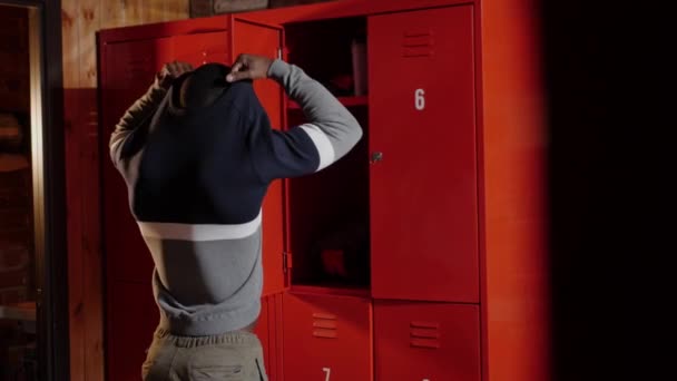 Hombre joven atlético afroamericano cambiándose en el vestuario en el gimnasio — Vídeo de stock