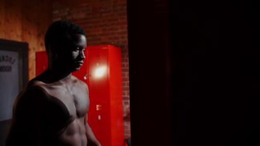 Soyunma odasında duran Afro-Amerikan atletik genç adam.