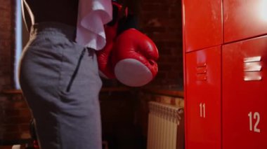 Afro-Amerikan atletik yarı çıplak genç adam dolabını açar ve boxer eldivenlerini giyer - kameraya bakar