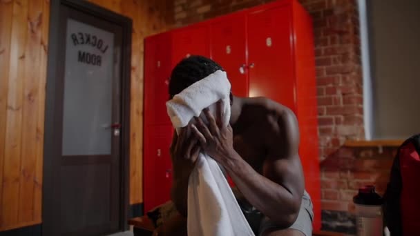 Afro-Amerikaanse atletische jongeman veegt zijn gezicht af met een handdoek — Stockvideo