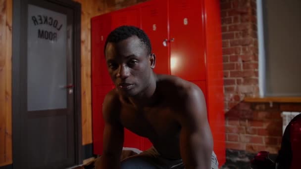 African-american athletic young man sitting in locker room and looking in the camera — Stock Video