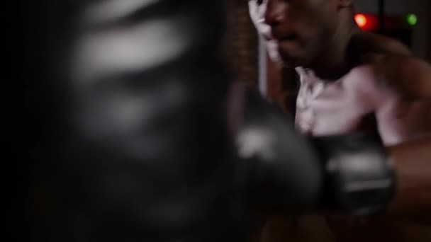 Afroamerikan atletisk skjorta ung man boxare utbildning på slagsäck med en insats i gymmet — Stockvideo