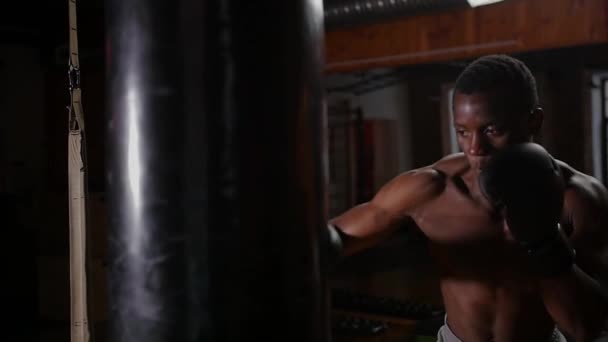 Preto shirtless homem boxer formação perfuração no saco de perfuração no ginásio — Vídeo de Stock