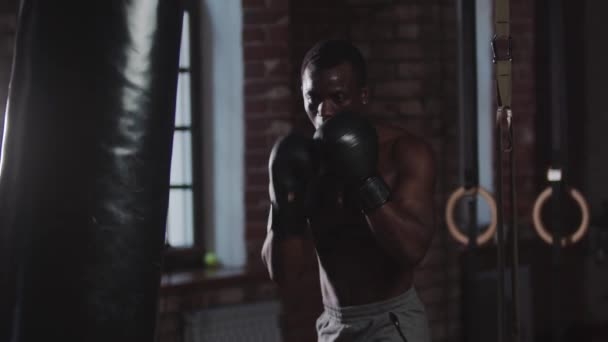 Treinamento de ginástica - um homem bonito preto perfurando o saco de perfuração — Vídeo de Stock
