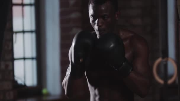 Treinamento de ginástica - um jovem bonito preto perfurando o saco de perfuração — Vídeo de Stock