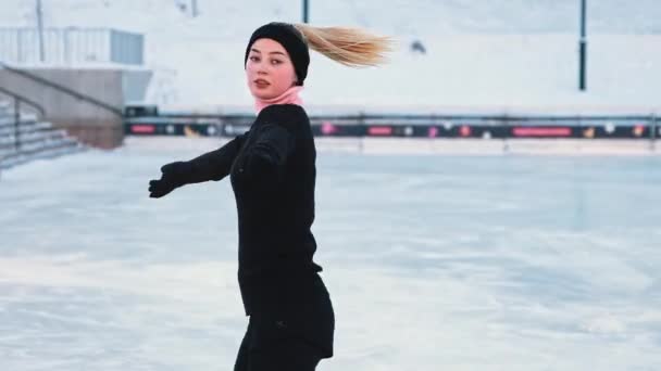 Joven mujer rubia patinaje artístico en pista de hielo pública — Vídeos de Stock