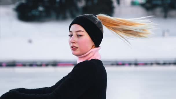 年轻美丽的女人在溜冰场上滑冰，看着镜头 — 图库视频影像