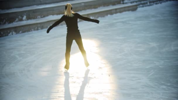 Eislaufen - junge blonde Eiskunstläuferin am Morgen auf der öffentlichen Eisbahn — Stockvideo