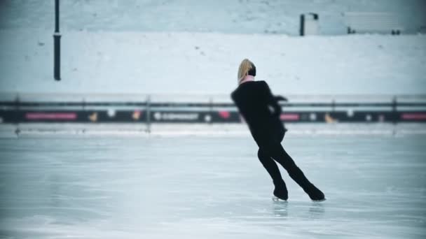 Patinaje sobre hielo - mujer rubia joven con alta cola de caballo patinaje artístico en la pista de hielo pública — Vídeos de Stock
