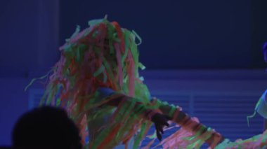 Küçük çocuklar kurdelelerle oynarken gösteri neon odada