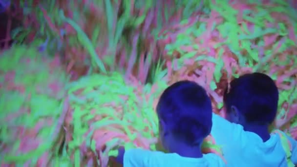 Uroczystości urodzinowe - małe dzieci i animatorzy wymiotujące kolorowe wstążki w neonowym oświetleniu — Wideo stockowe