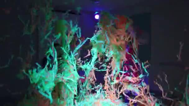 Verjaardagsfeest - kleine kinderen spelen met kleurrijke linten in neon verlichting in de kamer — Stockvideo