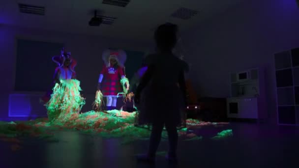 Verjaardagsfeest in neon kamer - kleine kinderen spelen met kleurrijke linten in neon verlichting — Stockvideo