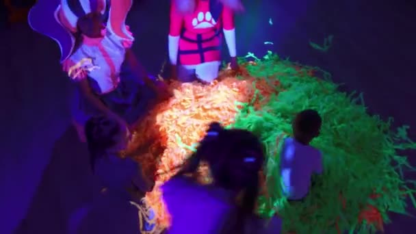 Celebração de aniversário - crianças brincando com fitas verdes e laranja na iluminação de néon — Vídeo de Stock
