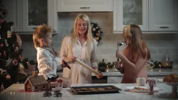 Rodzinne święta - mama i jej dzieci bawią się w kuchni - dziewczyna śpiewająca na chochli — Wideo stockowe