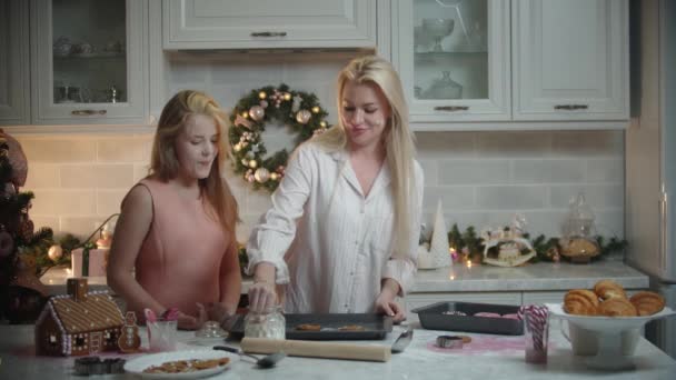 Rodzinne święta - mama i jej córka robią ciasteczka - polewają mąkę na wierzch ciasteczek - uderzając w piątkę — Wideo stockowe
