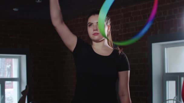 Νεαρή γυμνάστρια παίζει με πολύχρωμη κορδέλα στο στούντιο — Αρχείο Βίντεο