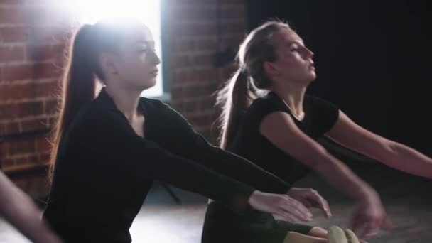 Fitness - trzy młode kobiety siedzące na podłodze, rozciągające się na palcach i trzymające je — Wideo stockowe